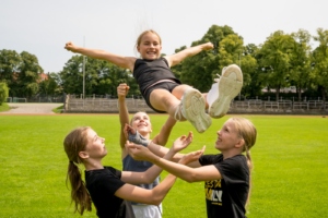 Mehrere Cheerleaderinnen fangen eine Athletin bei einem Cradle nach einem Stunt.